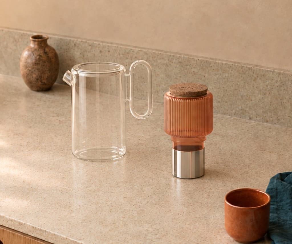 The omomi glass pitcher and coral filter housing on a stone counter